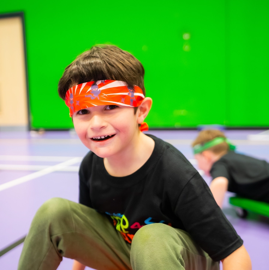 Smiling child wearing a headband during indoor games at Southend Holiday Camp