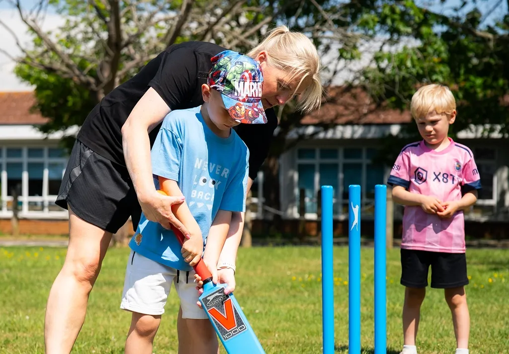 Camp 4 Champs coach helping children play cricket at an outdoor holiday camp