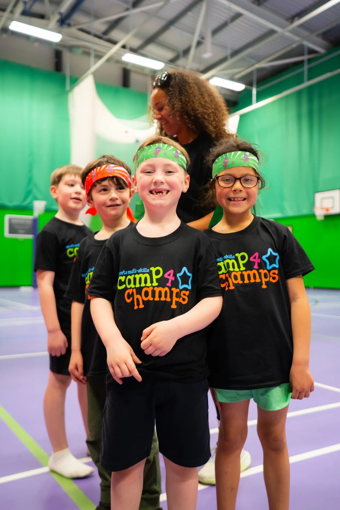 Children in Camp 4 Champs T-shirts smiling during an indoor holiday camp activity session